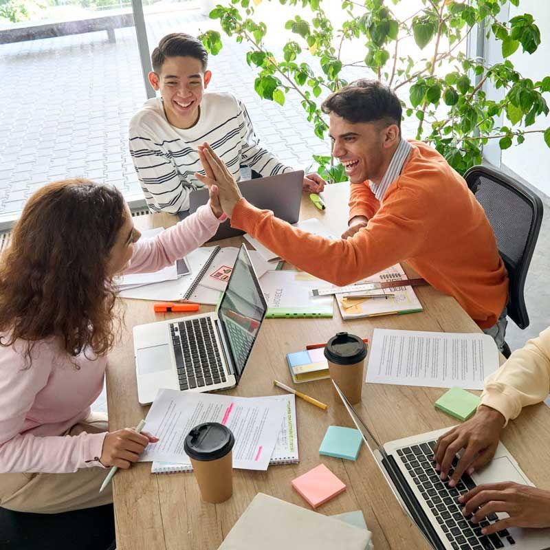 Happy students around table, High-fiving.